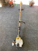 Full view of gas string trimmer showing orange shaft and engine