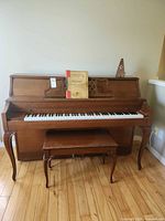 Full view of upright piano with bench and accessories