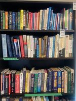 Three shelves densely filled with assorted hardcover and paperback books
