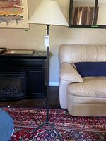 Full view of lamp including black metal base and beige shade
