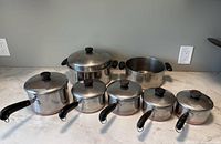 Cookware set front view with lids on showing sizes and handles