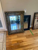 Both mirrors standing; ornate gold mirror front, black mirror behind