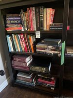 Books on three shelves including French dictionary, Uriel's Machine, Outdoor Building Book, Cambridge Encyclopedia, Atlas of Canada