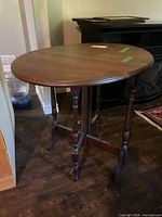 Full view of oval wooden drop-leaf table on dark floor