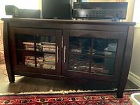 Front view of wooden media console showing glass doors, metal handles, and overall finish