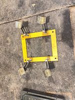 Full view of rectangular yellow frame with four adjustable clamp arms attached