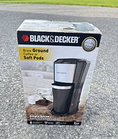 Front of original box displaying coffeemaker and travel mug