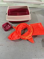 Litter box, bowl and orange fish tunnel displayed on floor