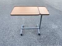 Full view of overbed table showing two-tier tops and metal base with casters