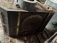Stove lying on pallet showing perforated side panels and round front door