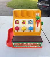 Front view of Fisher-Price cash register showing multicolor buttons, red tray and overall condition