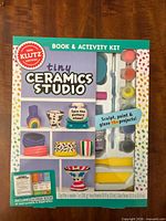 Front of Klutz Tiny Ceramics Studio box showing branding and window view of paints, tools and booklet