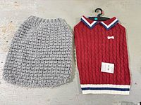 Gray crocheted sweater next to red cable knit sweater