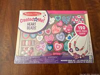 Front of sealed Melissa & Doug Wooden Heart Beads kit showing assorted heart beads and 120 piece count