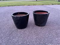 Pair of black glazed ceramic planters side by side on pavement