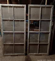 Front view of two matching 8-pane wood windows standing upright