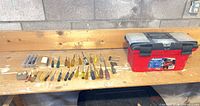 Workbench view showing red plastic toolbox and array of screwdrivers, tape measure, bit box, hex keys