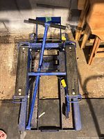 Top view of blue hydraulic lift showing twin rubber-padded platforms, pump handle and frame