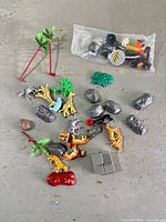 Group shot of all items spread on floor, showing animals, rocks, palm trunks, foliage and bagged bricks