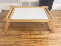 Tray standing on legs showing white laminate top and wood frame
