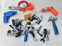 Group view showing circular saw, blue drill, orange screwdriver, hammer and large assortment of fasteners
