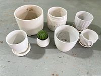 All seven white ceramic planters with saucers displayed