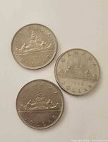 Three 1968 Canadian Voyageur dollar coins grouped on white background