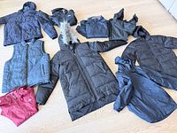 Nine coats and vest laid out on floor