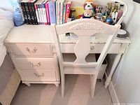 Front view of off-white wooden desk with three drawers and matching chair pushed in