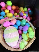 Basket with decorative egg and numerous plastic eggs inside black tote