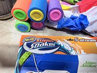 Close-up of Nerf Super Soaker box, mini foam noodles and part of beach ball