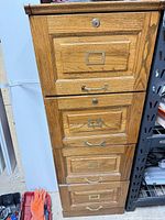 Front view of five-drawer oak file cabinet showing brass hardware and top lock