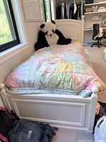 Front angled view of white twin bed frame, top mattress visible