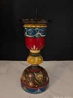 Full view of candle holder showing painted wooden body and metal drip plate