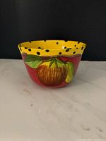 Front view showing hand-painted fruit design, red body, yellow polka-dot rim