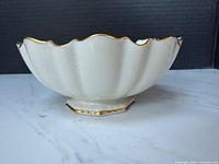 Side view showing scalloped shape, pedestal base, gold trim