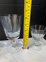 Tall goblet and short cordial glass beside tape measure showing heights