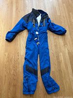Full view of blue Bogner one-piece ski suit laid flat