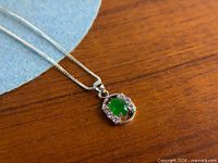 Close-up of pendant showing green center stone and clear CZ accents