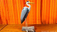 Full view of carved heron sculpture on driftwood base