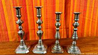 Front view of four brass candlesticks showing two different designs