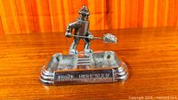 Front view showing Iron Fireman figure, shovel, twin ashtray recesses, raised branding