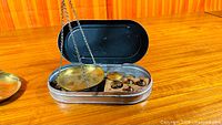 open metal case showing brass pan, wood block with weights