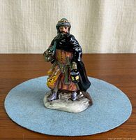 Front view of figurine showing lantern, gifts and detailed robes
