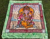 Full view of square Ganesha tapestry laid flat showing design, colours, and fringe
