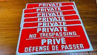 Stack of six identical red bilingual private property sticker signs