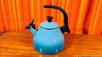 Front view of turquoise Le Creuset whistling kettle on wood surface