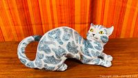 Full left side view of ceramic cat showing striped pattern and curled tail