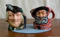 Front view of both character jugs showing faces and handles