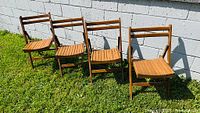 Four matching folding ladder-back wooden chairs outdoors